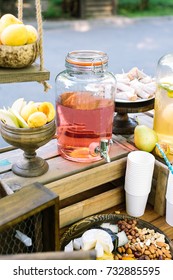 country lifestyle, drinks, rural products concept. generous amount of wonderful confection in wooden vases surrounding huge jar with bright pink homemade compot