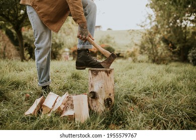 Country Man Splitting Wood With Axe On The Field