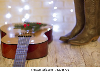 Country Music Christmas With Acoustic Guitar And Cowboy Shoes On Wood Table