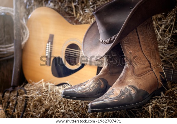 Country music festival live\
concert or rodeo with cowboy hat guitar and boots in barn\
background