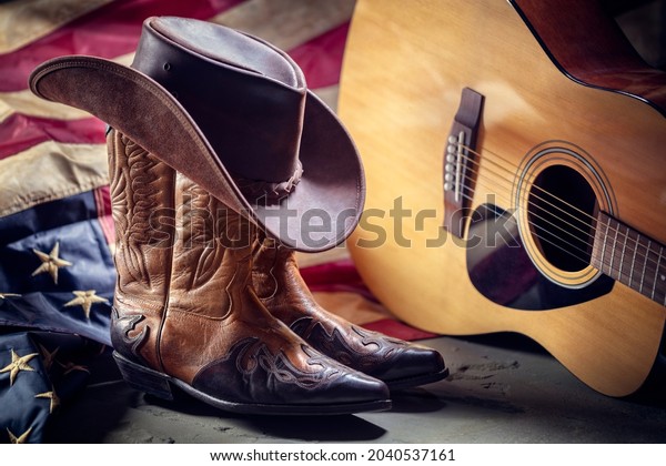 Country music festival live\
concert with acoustic guitar, antique american flag, cowboy hat and\
boots