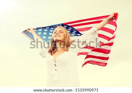 country, patriotism, independence day and people concept - happy smiling young woman in white dress with national american flag outdoors