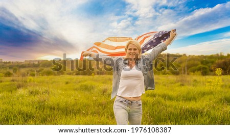 country, patriotism, independence day and people concept - happy smiling young woman with national american flag on field