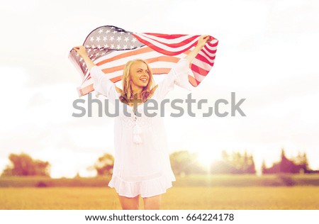 country, patriotism, independence day and people concept - happy smiling young woman in white dress with national american flag on cereal field