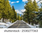 Country road in the forest in a winter sunny day morning. Mount Girouard in the background. Banff National Park, Canadian Rockies, Alberta, Canada.