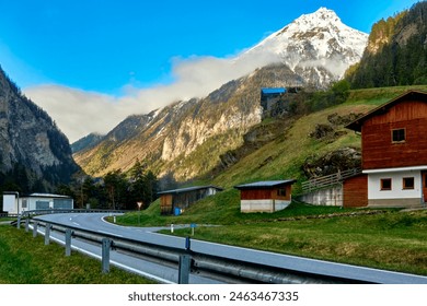 Country Road in Front of a Mountain Hut in the Austrian Alps with a Snow-Capped Peak in the Background - Powered by Shutterstock