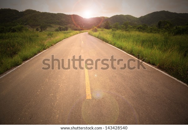 Country road to mountain with sun flare in\
concept go to target go to your\
destination