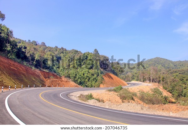 The country road in the mountains curve as an\
arrow on the background\
forest