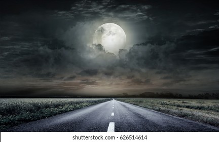 country road at night with large moon