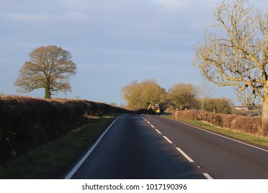 Country Road On A Winters Day Farmer Cutting Hedge Row With Tractor