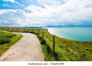 A country road through the valley near the cliffs of the English Channel. Green grass, azure water, clear blue sky. Idyllic summer scene. Cap Gris Nez, Pas-de-Calais, France