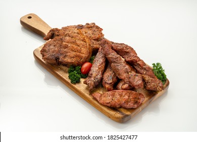 Country Style Ribs And Pork Steaks On A Wood Cutting Board, Isolated On White Background.