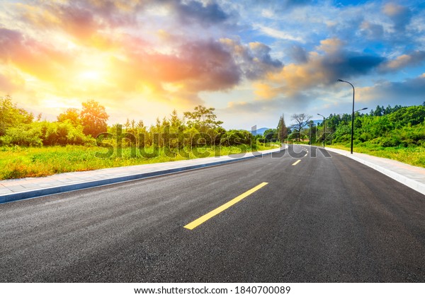 Countryside asphalt road and green\
plants with mountain natural scenery in Hangzhou at\
sunrise.