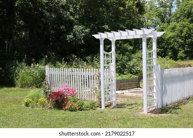 Countryside flower garden with white trellis arbor and colorful blooms