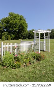 Countryside Flower Garden With White Trellis Arbor And Colorful Blooms With Clear Blue Sky