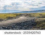 Countryside gravel road and green grassland with mountain nature landscape in summer. Road trip.