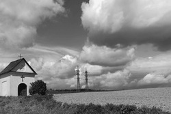 Countryside Landscape, Small Chapel At The Field, In The Background Of High Voltage And Heaven With Clouds, Outdoor, Black And White Photo