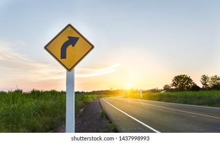 Countryside road ,Sign curved road on the way at the natural Sunset Sunrise Over Field Or Meadow. Countryside Landscape Under Scenic Colorful Sky At Sunset Dawn Sunrise. Warm Colours.