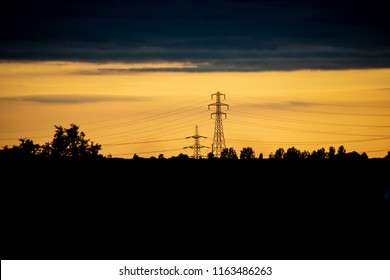 Countryside scene of fields and electricity pylons against the golden sunset sky - Powered by Shutterstock