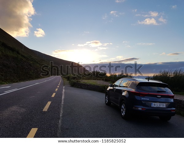 County Kerry, Ireland - 12 SEPTEMBER 2018 : Vehicle\
stop at parking at one of the scenic road in Ring of Kerry to enjoy\
sunset view.