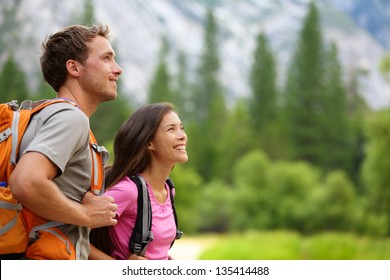 Couple - active hikers hiking enjoying view looking at mountain forest landscape in Yosemite National Park, California, USA. Happy multiracial outdoors couple, young Asian woman and Caucasian man.
