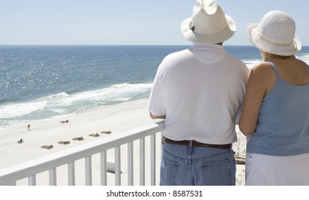 A Couple Admiring The Beach From Their Balcony.