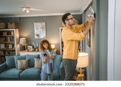 Couple adult caucasian man and woman at home connecting setup and install cctv security video surveillance camera monitoring system - Shutterstock ID 2320388075