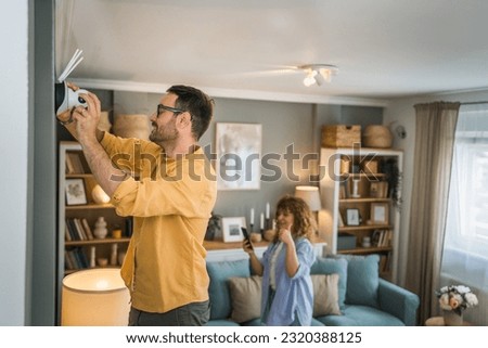 Couple adult caucasian man and woman at home connecting setup and install cctv security video surveillance camera monitoring system