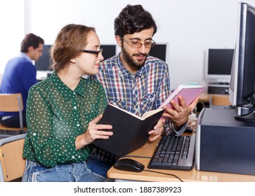 Mehrere erwachsene Schüler, die zusammen das Lehrbuch lesen, während sie in der Computerschule studieren.