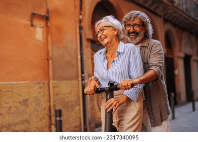 A couple of affectionate pensioners are outdoors in the city, bonding and riding on electric scooter. - Powered by Shutterstock