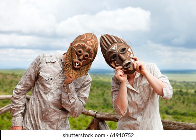 Couple In African Masks Standing At Balcony With View To Savanna