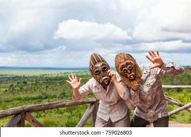 Couple In African Masks Standing At Balcony With View To Savanna