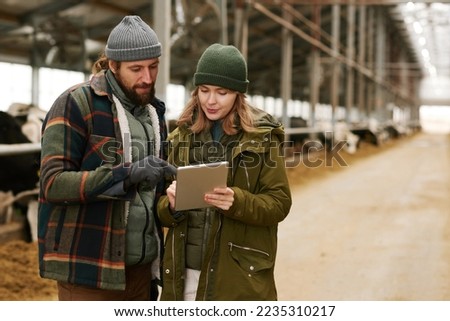 Couple of agronomists using computer tablet on farm