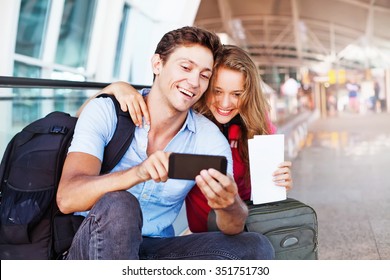 couple in airport using travel app on smart phone