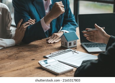 A couple is approaching a housing project to buy, and they are discussing details and advice with a salesperson in a housing project. Real estate trading ideas with couples. - Shutterstock ID 2165317803