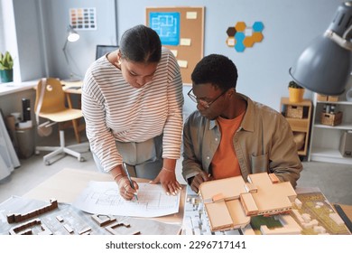 Couple of architects drawing blueprint of building in team and developing mockups - Powered by Shutterstock