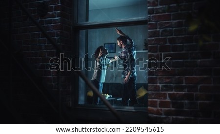 Couple Arguing and Fighting Horribly. Domestic Violence and Emotional abuse Scene, Stressed Woman and Aggressive Man Screaming at Each other in Dark Apartment. Dramatic Scene. Shot from Outdoors.