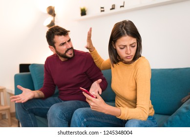 Couple arguing, having relationship problems. Boyfriend and girlfriend fighting, man yelling at woman while she is turning her head and holding phone. Divorce concept.
