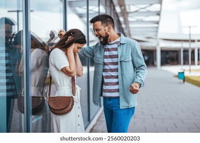 A couple arguing outdoors next to a glass wall, showing emotions like anger and distress. Visualizes conflict in relationships and highlights dramatic expressions during disagreements. - Powered by Shutterstock