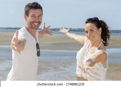 Couple With Arms Wide Open Enjoying The Ocean