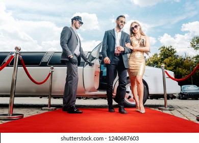 Couple arriving with limousine walking red carpet, a driver is opening the car door