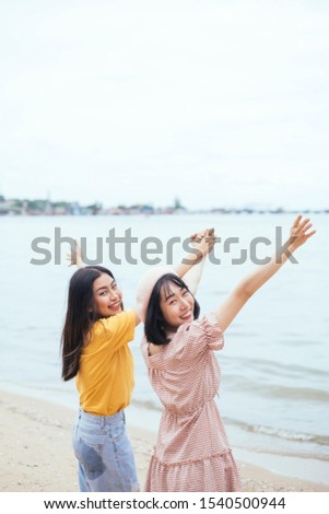 Couple of asian bestfriend on casual costume holding hand up in the sky on the beach.
