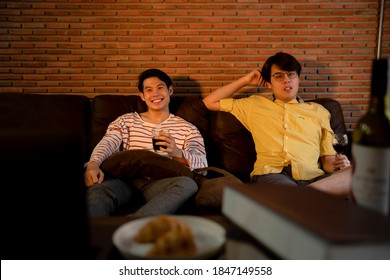 Couple Of Asian LGBTQ+ Men Enjoy Wine And Watch TV Program Together At Home.