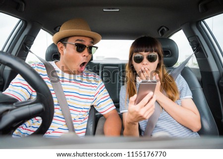 Couple asian man and woman sitting in car and looking at smartphone feel shocked . Travel concept.