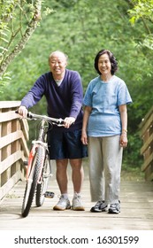 A Couple Asian Mature Talking While Walking And Exercising At A Park