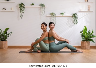 Couple Asian young woman sitting back to back on yoga mat smile and laughing after exercise yoga together.Happiness of two healthy female relax after finished workout at cozy home.Healthy lifestyle - Powered by Shutterstock