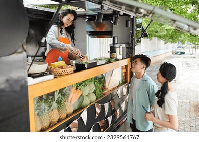 Couple asking food truck worker to add extra ingredients in sandwiches - Powered by Shutterstock