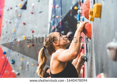 couple of athletes climber moving up on steep rock, climbing on artificial wall indoors. Extreme sports and bouldering concept