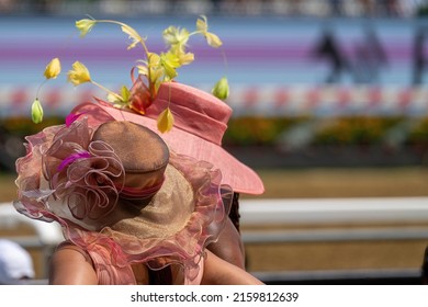 A Couple Of Attendees At A Horse Race, Wearing Fancy Hats.