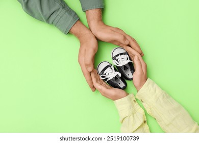 Couple with baby booties on green background, top view - Powered by Shutterstock